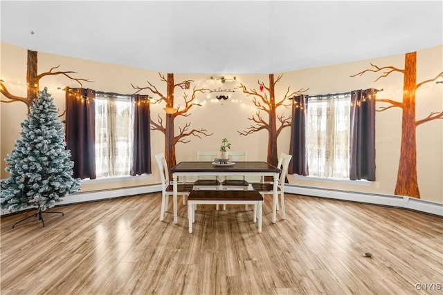 dining room with wood-type flooring, baseboard heating, and a healthy amount of sunlight