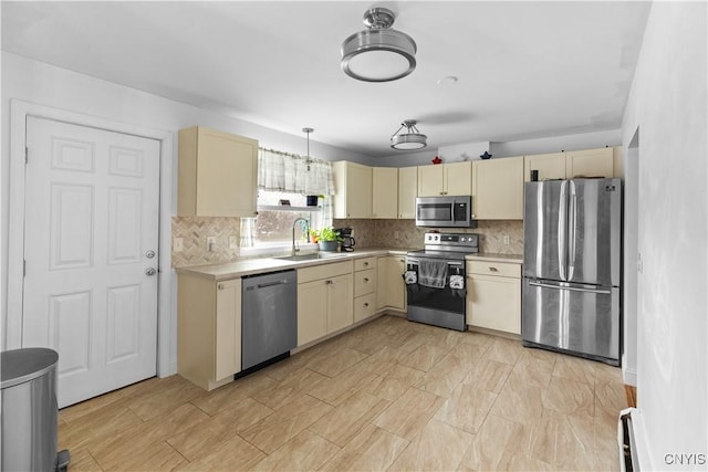 kitchen featuring pendant lighting, backsplash, sink, baseboard heating, and appliances with stainless steel finishes