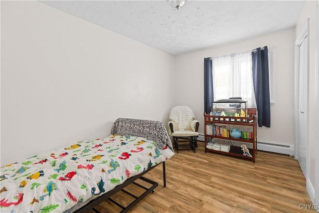 bedroom featuring wood-type flooring and a baseboard radiator