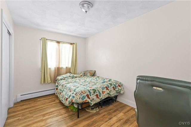 bedroom with a baseboard radiator and hardwood / wood-style flooring