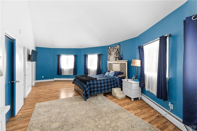 bedroom with hardwood / wood-style flooring and a baseboard heating unit