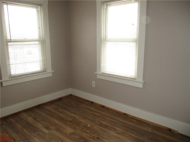 empty room with plenty of natural light and dark hardwood / wood-style floors