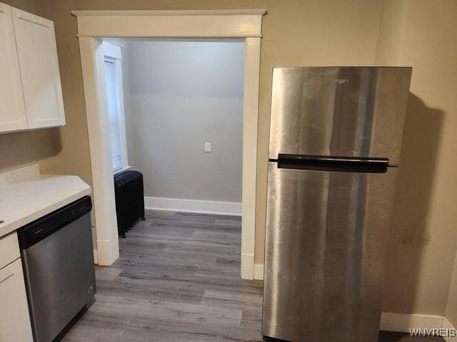 kitchen with light hardwood / wood-style flooring, white cabinets, and appliances with stainless steel finishes