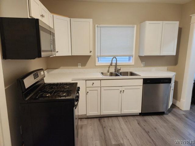 kitchen featuring light hardwood / wood-style floors, white cabinetry, sink, and appliances with stainless steel finishes