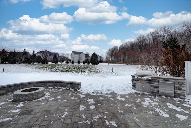 yard covered in snow with exterior kitchen, an outdoor fire pit, and a patio