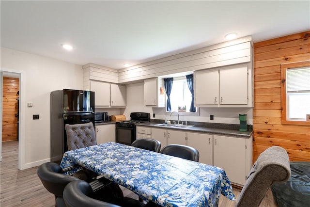 9539 Bronson Rd, Dansville, NY 14572 - kitchen featuring sink, white cabinets, wood walls, and black appliances