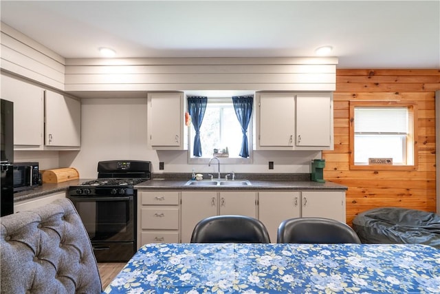 9539 Bronson Rd, Dansville, NY 14572 - kitchen with black appliances, white cabinets, wood walls, and sink
