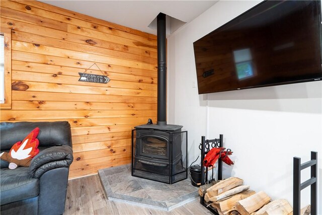 9539 Bronson Rd, Dansville, NY 14572 - living room featuring hardwood / wood-style floors, wood walls, and a wood stove