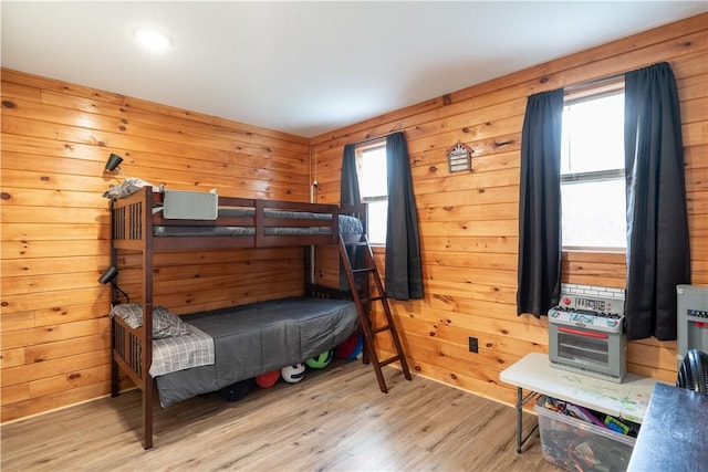 9539 Bronson Rd, Dansville, NY 14572 - bedroom featuring multiple windows, wood walls, and light wood-type flooring
