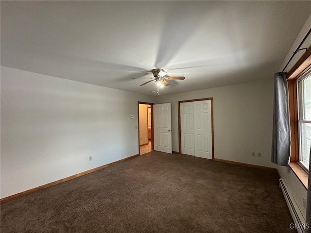 unfurnished bedroom with ceiling fan, baseboard heating, multiple windows, and dark colored carpet