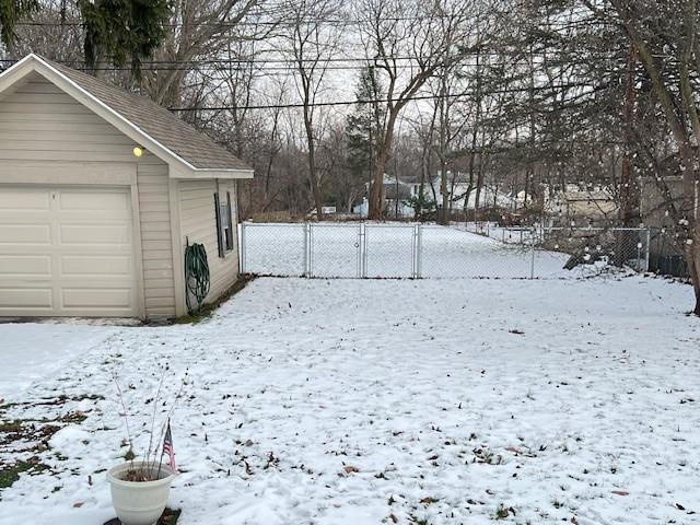 yard layered in snow featuring a garage and an outdoor structure