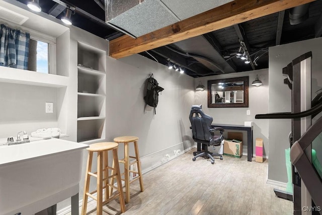 office space with sink, rail lighting, light hardwood / wood-style floors, and built in features