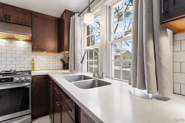 kitchen with sink, stainless steel range with gas cooktop, decorative backsplash, a wealth of natural light, and pendant lighting