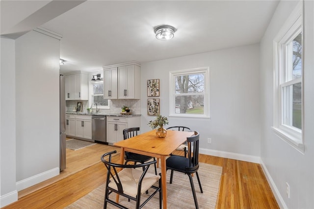 dining room with light hardwood / wood-style flooring, a healthy amount of sunlight, and sink