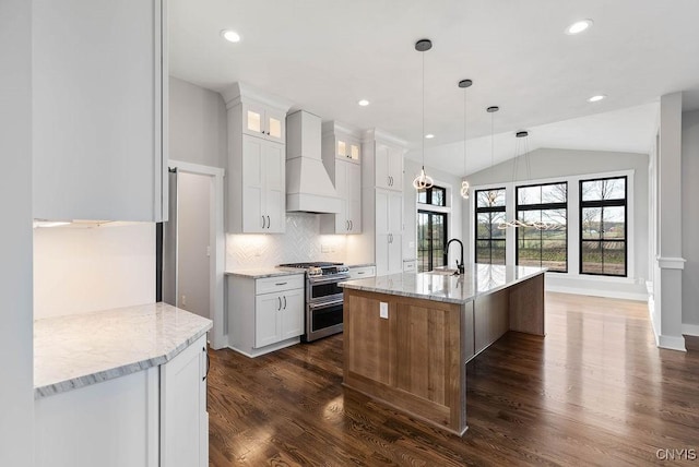 kitchen with range with two ovens, white cabinetry, lofted ceiling, and custom range hood