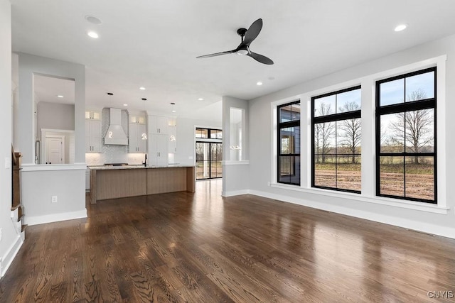 unfurnished living room with ceiling fan, a healthy amount of sunlight, and dark hardwood / wood-style floors