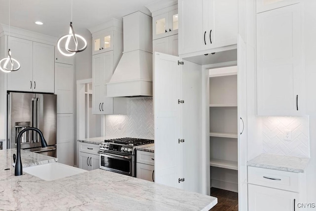 kitchen featuring stainless steel appliances, white cabinetry, custom range hood, backsplash, and pendant lighting