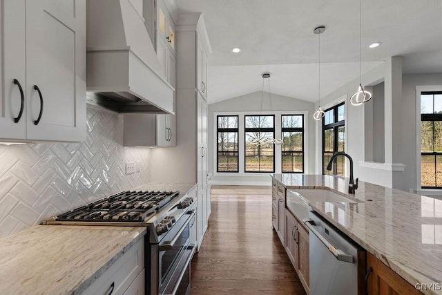 kitchen with light stone counters, decorative light fixtures, stainless steel appliances, lofted ceiling, and white cabinets