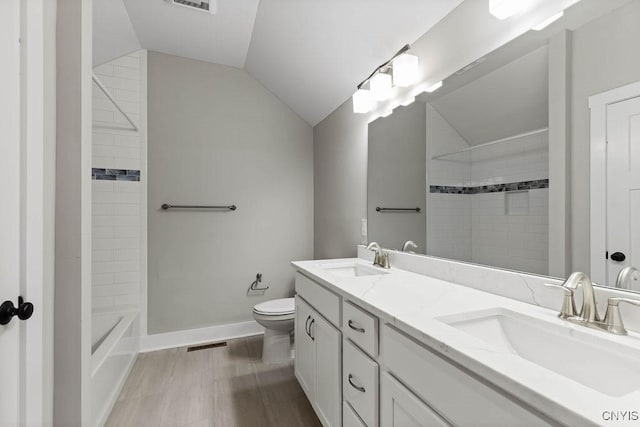 bathroom with wood-type flooring, vaulted ceiling, vanity, and toilet