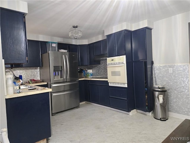 kitchen featuring sink, a chandelier, white oven, and stainless steel refrigerator with ice dispenser