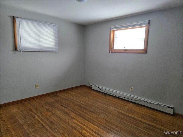 spare room featuring baseboard heating and dark hardwood / wood-style floors