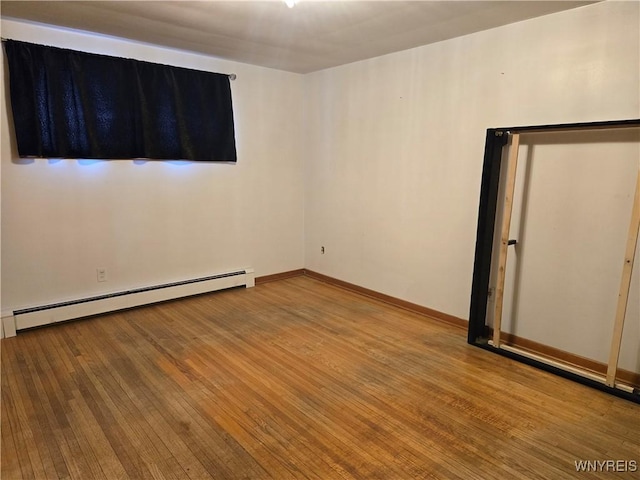 spare room with wood-type flooring and baseboard heating