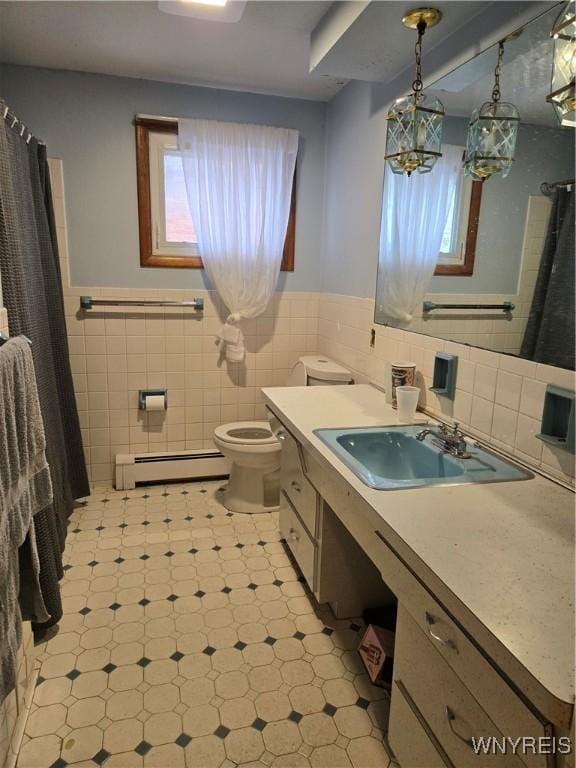 bathroom with tile walls, toilet, a wealth of natural light, and a baseboard heating unit