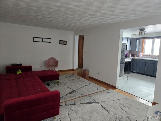 living room featuring a textured ceiling, ceiling fan, light hardwood / wood-style flooring, and sink