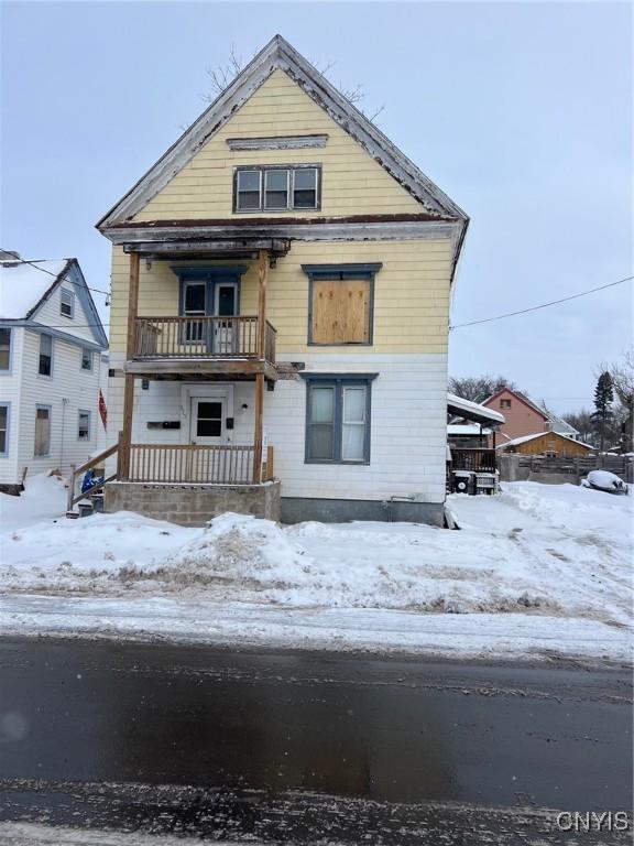 snow covered house featuring a balcony