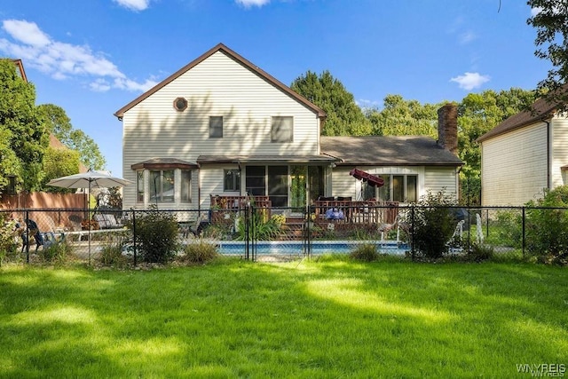 back of house featuring a lawn and a fenced in pool