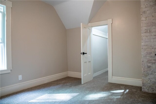 additional living space featuring vaulted ceiling and carpet flooring