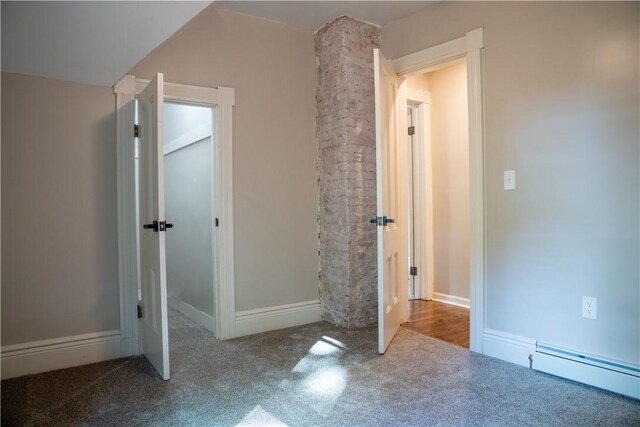 unfurnished bedroom with lofted ceiling, a baseboard heating unit, and carpet floors