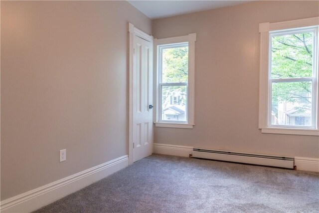 empty room featuring carpet flooring, a baseboard radiator, and a wealth of natural light