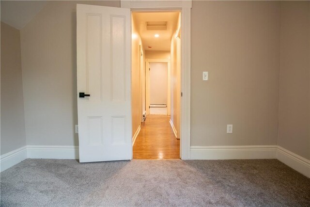 carpeted empty room with a baseboard radiator