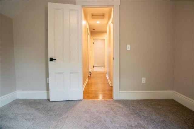 carpeted empty room featuring baseboard heating