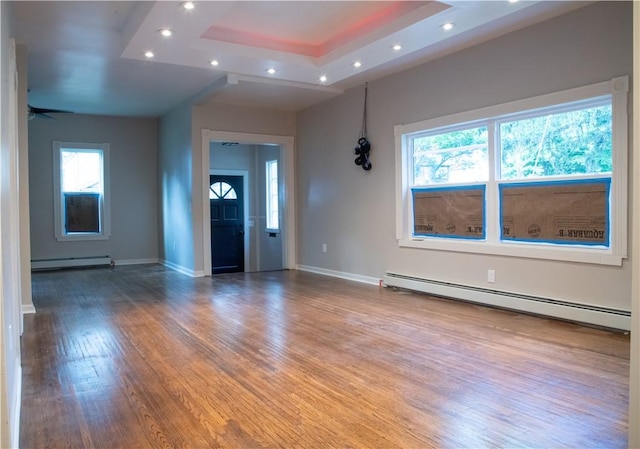 entrance foyer with a raised ceiling, a baseboard heating unit, and plenty of natural light