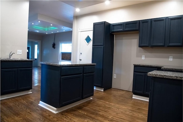 kitchen with dark stone countertops, dark hardwood / wood-style flooring, and sink