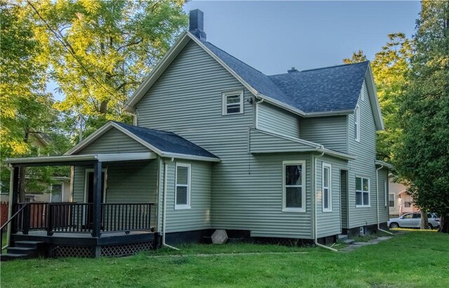 rear view of property featuring covered porch and a lawn