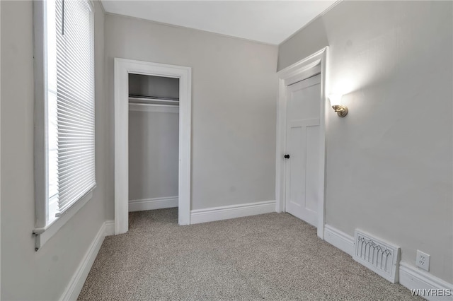 unfurnished bedroom featuring a closet and light carpet