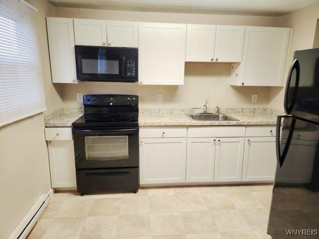 kitchen with black appliances, light stone countertops, a baseboard heating unit, sink, and white cabinetry