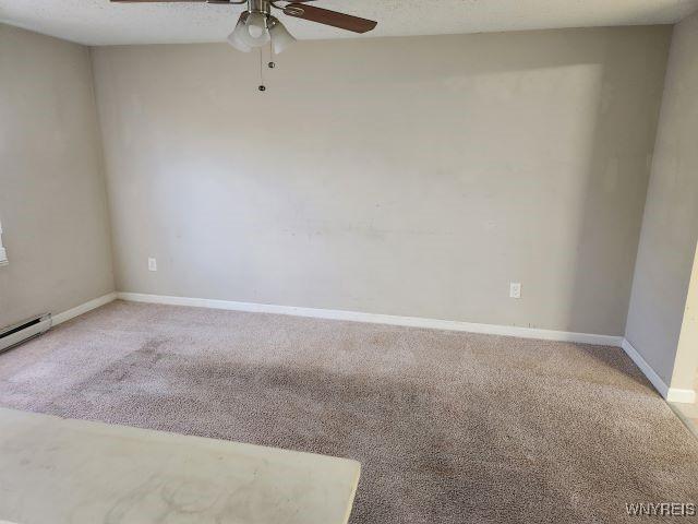 unfurnished room with ceiling fan, a baseboard radiator, and carpet floors