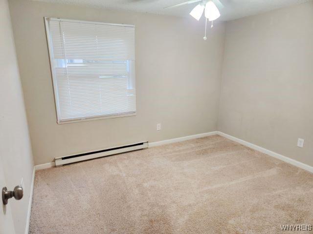 empty room featuring light carpet, baseboard heating, and ceiling fan