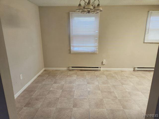 empty room featuring an inviting chandelier and baseboard heating