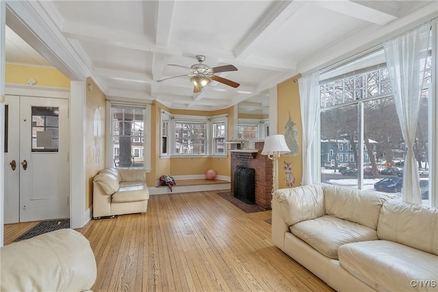 living room featuring coffered ceiling, a brick fireplace, ceiling fan, and a healthy amount of sunlight