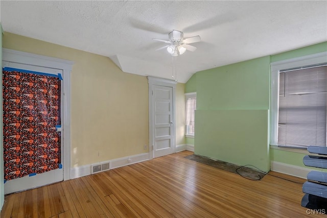 unfurnished room featuring a textured ceiling, ceiling fan, hardwood / wood-style floors, and vaulted ceiling