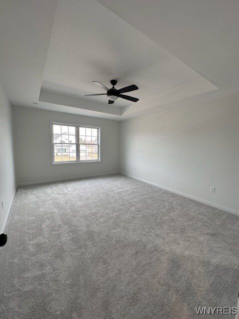 unfurnished room featuring ceiling fan, carpet, and a tray ceiling