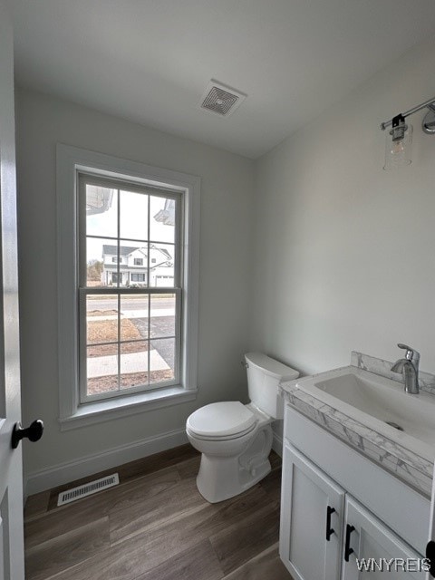 bathroom featuring plenty of natural light, toilet, hardwood / wood-style floors, and vanity