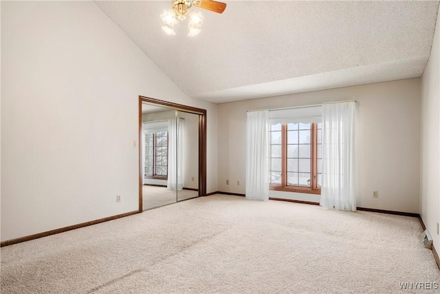 carpeted empty room featuring ceiling fan, a textured ceiling, and vaulted ceiling