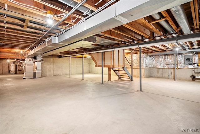 basement featuring electric panel, heating unit, and gas water heater