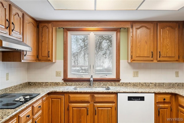 kitchen with black electric stovetop, tasteful backsplash, white dishwasher, light stone counters, and sink